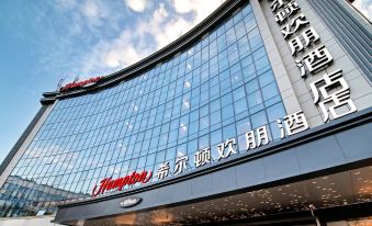 The front view of a hotel in Hong Kong with an illuminated sign at Hampton by Hilton Yiwu International Trade Market