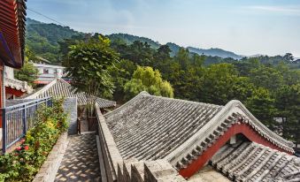 The view from a rooftop in an Asian city showcases mountains and hills in the background at Mutianyu Great Wall Hotel