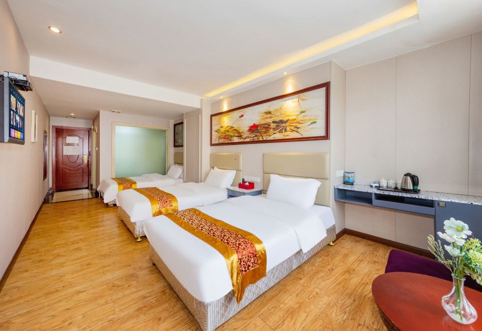 The bedroom features two double beds and a large flat-screen TV in the center at Mankedun Hotel (Guangzhou Sanyuanli Metro Station)