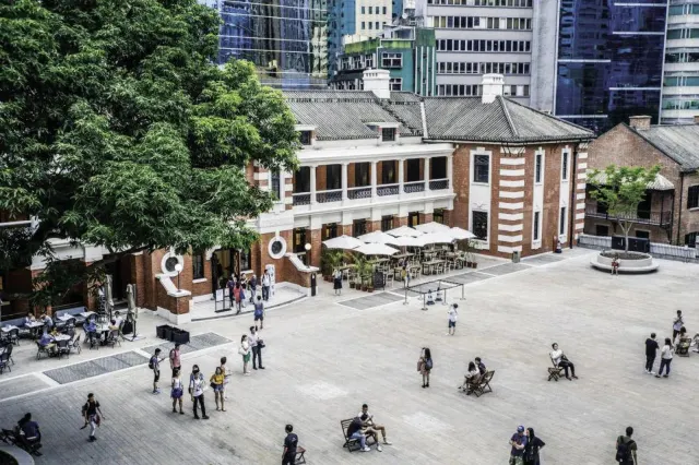 大館|中環荷李活道前中區警署建築群的檢閱廣場俯瞰,紅磚營房大樓與背後中環現代高樓形成強烈的新舊對比,園內另設當代美術館