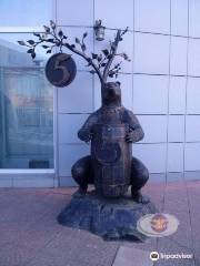 Скульптура медведя с бочонком, который стоит рядом с денежным деревом