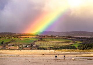 After a heavy rain, the sea recovered its calm and soft breeze, and the rainbow started to appear upon the beach as the sunlight returned.