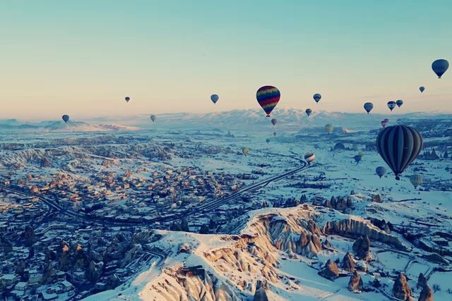 Hot air balloons flying all over the sky.