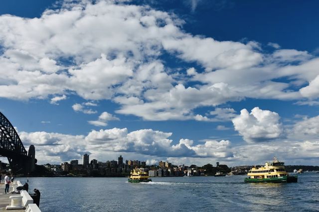 Sydney Opera House, Harbour Bridge, and clouds.