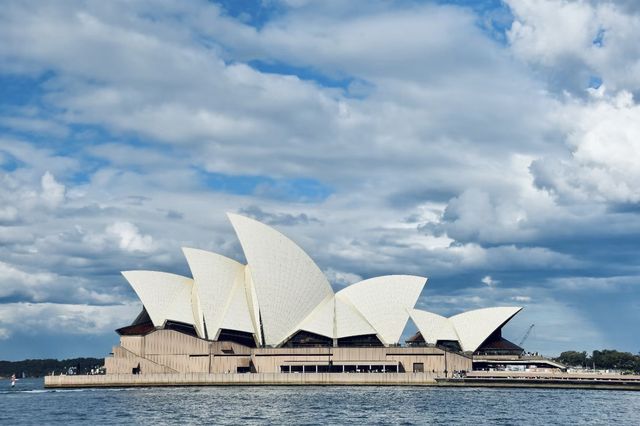 Sydney Opera House, Harbour Bridge, and clouds.