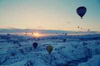 Hot air balloons flying all over the sky.