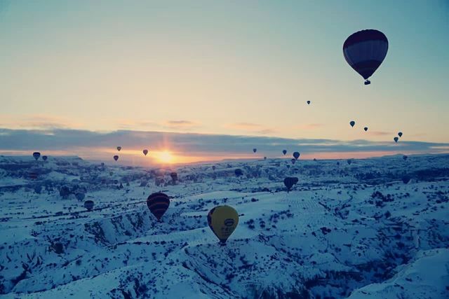 Hot air balloons flying all over the sky.
