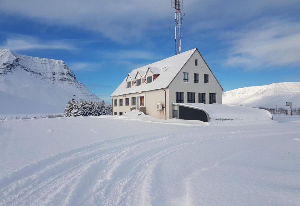 a white building with a radio tower on top is surrounded by snow and has a clear blue sky in the background at Holt Inn