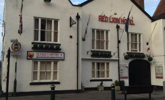 "a white building with multiple flags and a sign that reads "" big sam 's pub "" on the side of the road" at The Atherstone Red Lion Hotel