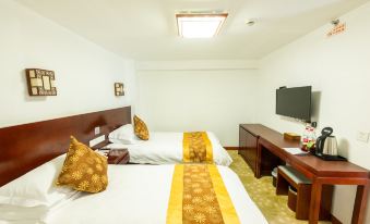 A bedroom is equipped with double beds and a large flat-screen TV positioned in the center at Guangmingding Hotel