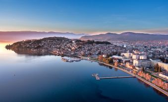 a beautiful cityscape with a large body of water , mountains in the background , and a pier extending into the scene at Villa Varosh