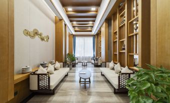 a modern living room with wooden furniture , including couches and tables , arranged around a central space at Tibet Hotel