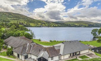 a large house with a courtyard is situated near a lake , surrounded by lush greenery at The Kenmore Club