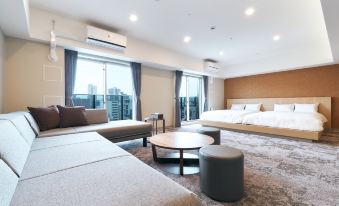 The bedroom has two beds and is connected to a living area with large windows at Stayat Osaka Shinsaibashi East