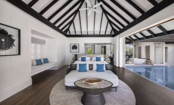 a spacious bedroom with a round bed , white walls , and a ceiling fan above it at Naladhu Private Island Maldives