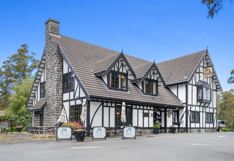 a large house with a black roof and white trim is surrounded by potted plants at The Fox and Hounds Historic Hotel