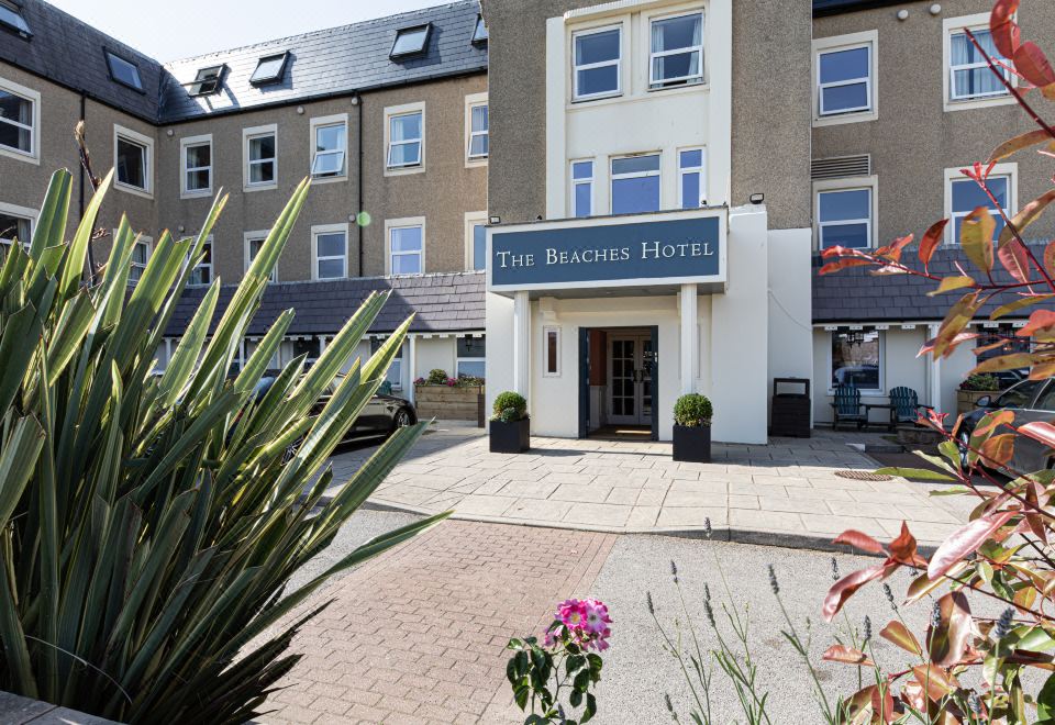 "a large hotel with a sign that reads "" the beachs hotel "" and several cars parked outside" at The Beaches Hotel