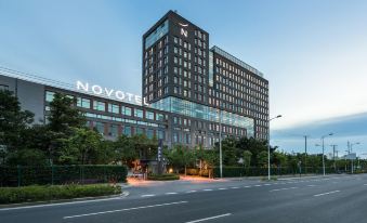 There is a large building with a visible exterior and a prominent name displayed in front at Novotel Shanghai Clover