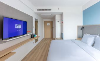 The modern bedroom features a double bed and a large flat-screen TV mounted on the wall at Holiday Inn Express Shanghai Pudong Airport