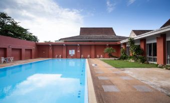 a red brick house with a swimming pool in the backyard , surrounded by grass and trees at The Imperial Narathiwat Hotel