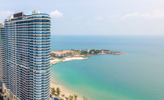 The balcony offers a view of buildings, a beach, and the ocean at Howard Johnson Plaza by Wyndham Blue Bay Sihanoukville