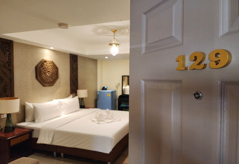 a hotel room with a king - sized bed , a bathroom , and a door leading to another room at Kim Hotel at Bangplong