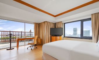 The room is furnished like an executive suite, featuring large windows, a bed, and a desk in the center at Radisson Collection Hotel, Yangtze Shanghai