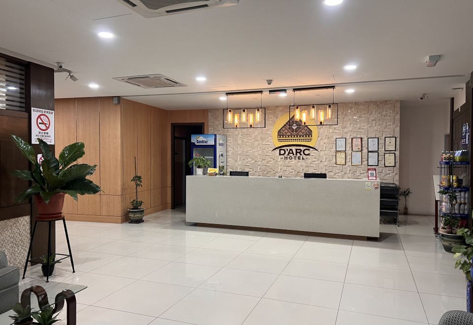 a modern office interior with a white reception desk , wooden paneling , and a large logo on the wall at D Arc Hotel