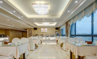 a large , well - lit room with white tablecloths and chairs , all set up for a formal event at Vienna Hotel