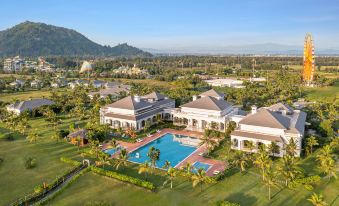 aerial view of a large house with a swimming pool , surrounded by palm trees and grass , in a tropical location at Melia Vinpearl Cua Sot Beach Resort