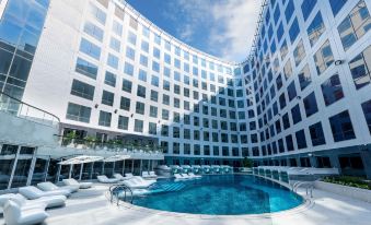 There is a large glass-fronted swimming pool located in front of the building at an upscale hotel or resort at Regala Skycity Hotel