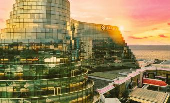 "a modern , curved building with a sign that says "" panama "" and the sun setting in the background" at Okada Manila