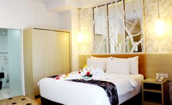 a large bed with white linens and a black throw is in a hotel room at Aquarius Boutique Hotel Sampit