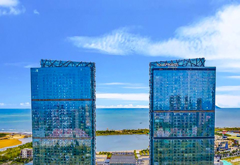 The city's skyline, featuring tall buildings against a backdrop of a blue sky, including one resembling a sail, provides an ideal location for a lavish hotel at Four Points by Sheraton Qingdao, West Coast