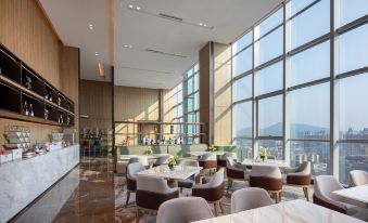 restaurant with ample natural light and centrally placed tables, accompanied by an adjacent open space at Junluxe Guangzhou Baiyun