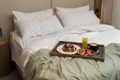 a tray with a plate of food and a cup of coffee is placed on a bed at Oval Hotel at Adelaide Oval, an EVT hotel