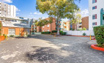 a parking lot in front of a building with trees and buildings in the background at APX Parramatta