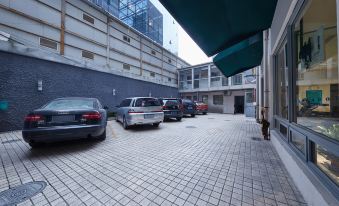 There is a large parking lot with several cars parked in the middle, and people walking on either side at Jinjiang Inn (Shanghai People's Square East Huaihai Road)