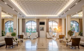 a spacious , well - lit lobby with white chairs and couches arranged around a central table , creating a welcoming atmosphere at Melia Vinpearl Cua Sot Beach Resort