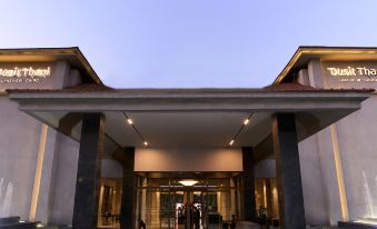 a woman in a red dress stands in front of a large building with two entrances at Dusit Thani LakeView Cairo