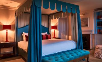 a bedroom with a blue canopy bed and a large white bed in the center of the room at Small Luxury Hotels of the World - the Mitre Hampton Court