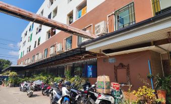 a row of parked motorcycles and bicycles are lined up in front of a building at Kim Hotel at Bangplong