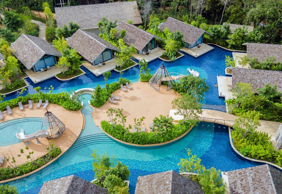 a resort with a large pool surrounded by multiple bungalows , providing a unique and relaxing atmosphere at Island Escape Burasari