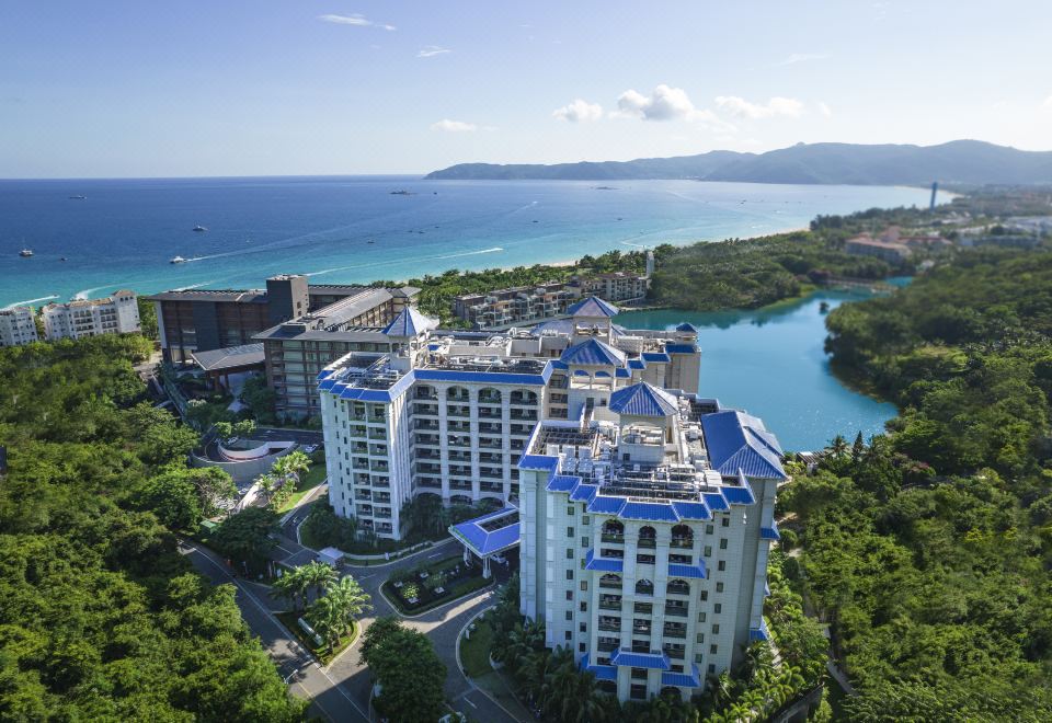 There is a large building situated next to a beautiful ocean, offering a stunning aerial view at Holiday Inn & Suites Sanya Yalong Bay