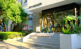 There is a store located on the sidewalk with large windows and plants in front of it at CITY PARK HOTEL