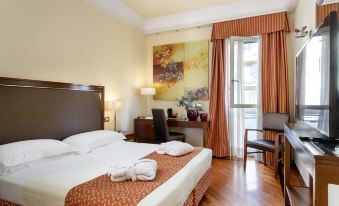 a large bed with a white and orange blanket is in the middle of a room with wooden floors , an open window , and a desk with at Grand Hotel Adriatico