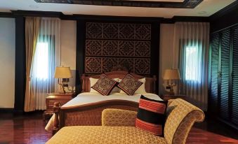 a large bed with a wooden headboard and footboard is in the center of a room with two lamps at Lanna Resort Chiang Mai