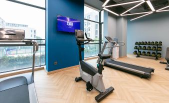 A spacious room equipped with exercise machines and wall-mounted flat screen TVs on the treadmill at Holiday Inn Express Shanghai Pudong Airport