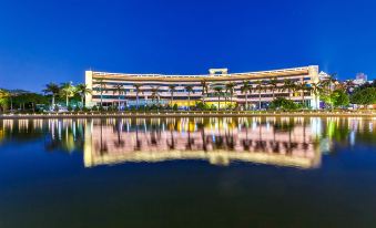 a large , multi - level building with a curved facade is reflected in the water at night at Swan Hotel