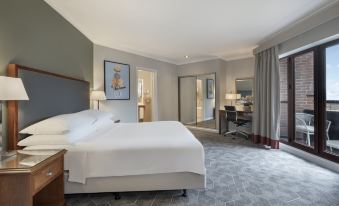 a large bed with white linens is in a room with gray and white carpeting at Delta Hotels Waltham Abbey